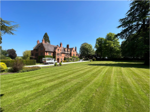 Large striped lawn beside a red brick building with trees and a white utility vehicle